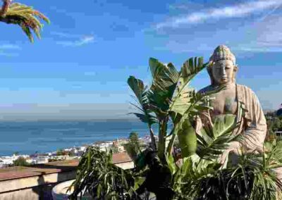 Ein Buddha sitzt auf einer Dachterrasse am Meer