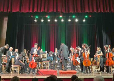 Opernbühne mit großem Orchester vor rot-grünem Samt-Vorhang