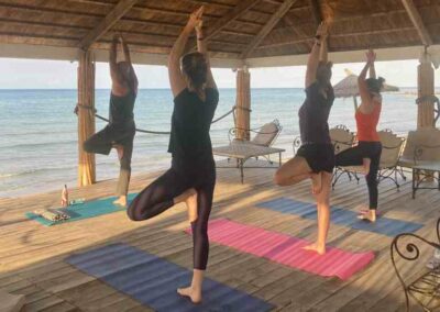 Eine Gruppe Yogis in Baumpose mit Blick aufs Meer