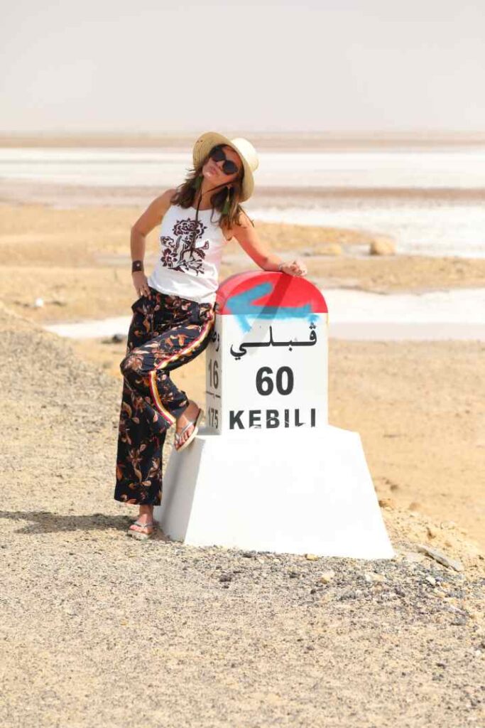 Frau steht vor Kilometerstein in Salzwüste