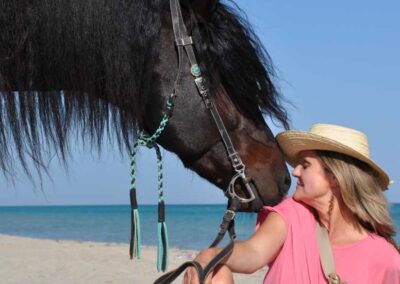 Pferd schnuppert an Frau am Strand