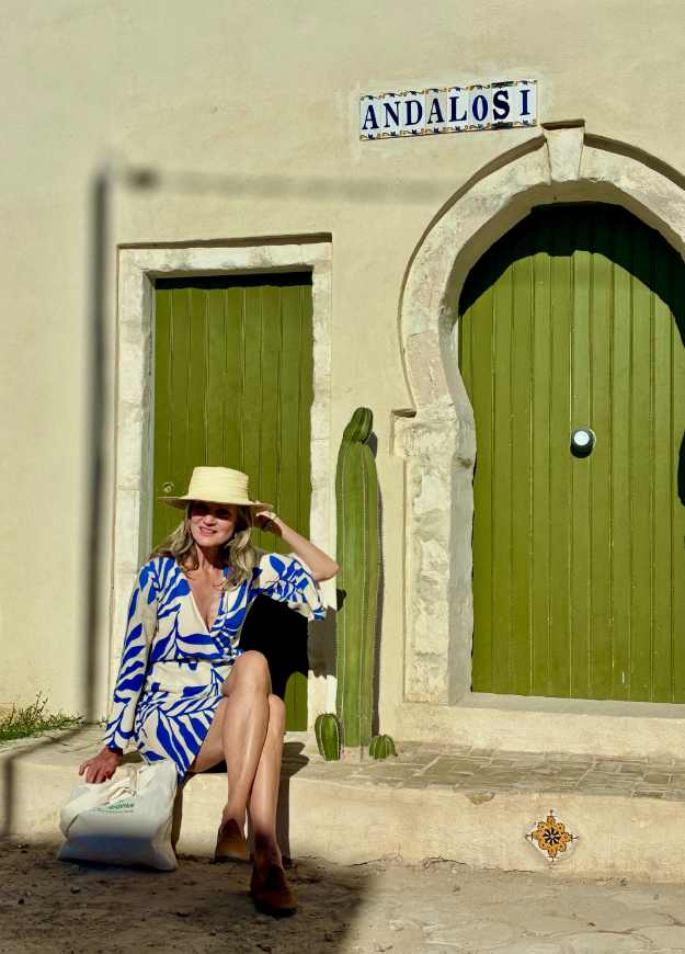 Frau sitzt vor einer grünen Tür neben Kaktus