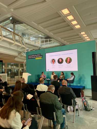 Podiumsdiskussion und Panel in einem Saal mit grüner Tafel im Hintergrund