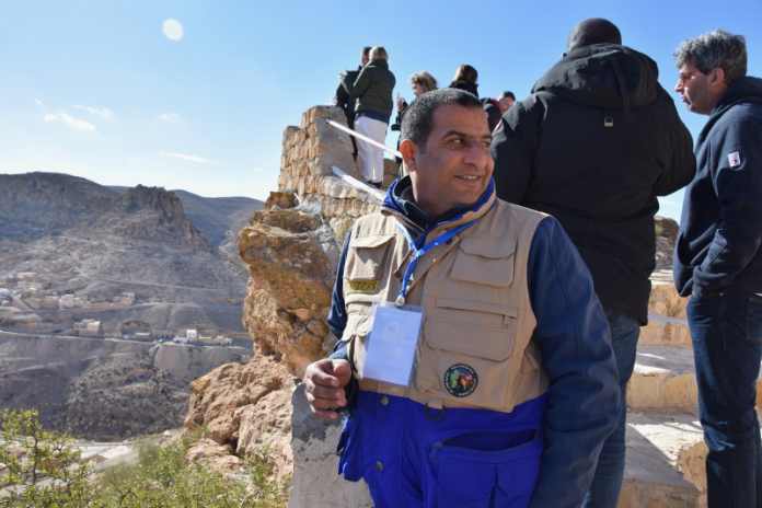 Ein Mann steht vor Gruppe und Gebirge