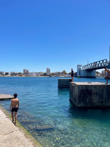 Hafenbecken mit Seebrücke und Mensch im Wasser